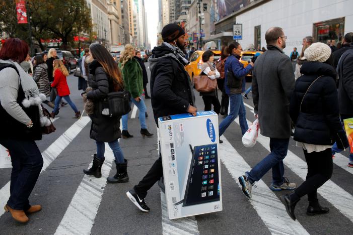A man carries a television across 6th Avenue during Black Friday sales in Manhattan, New York, U.S.