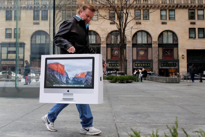 A man carries a newly purchased iMac from the Apple Fifth Avenue store during Black Friday sales in Manhattan, New York, U.S.